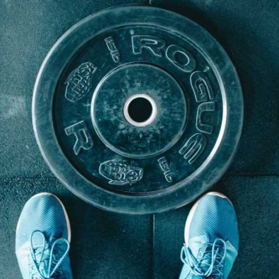black-steel-gym-plate view down on a black steel weight plate with blue shoes in front of it